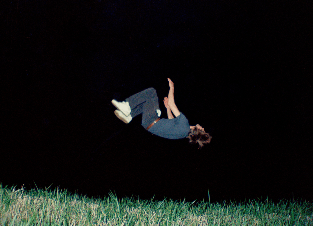 A photograph of a person mid backflip at night