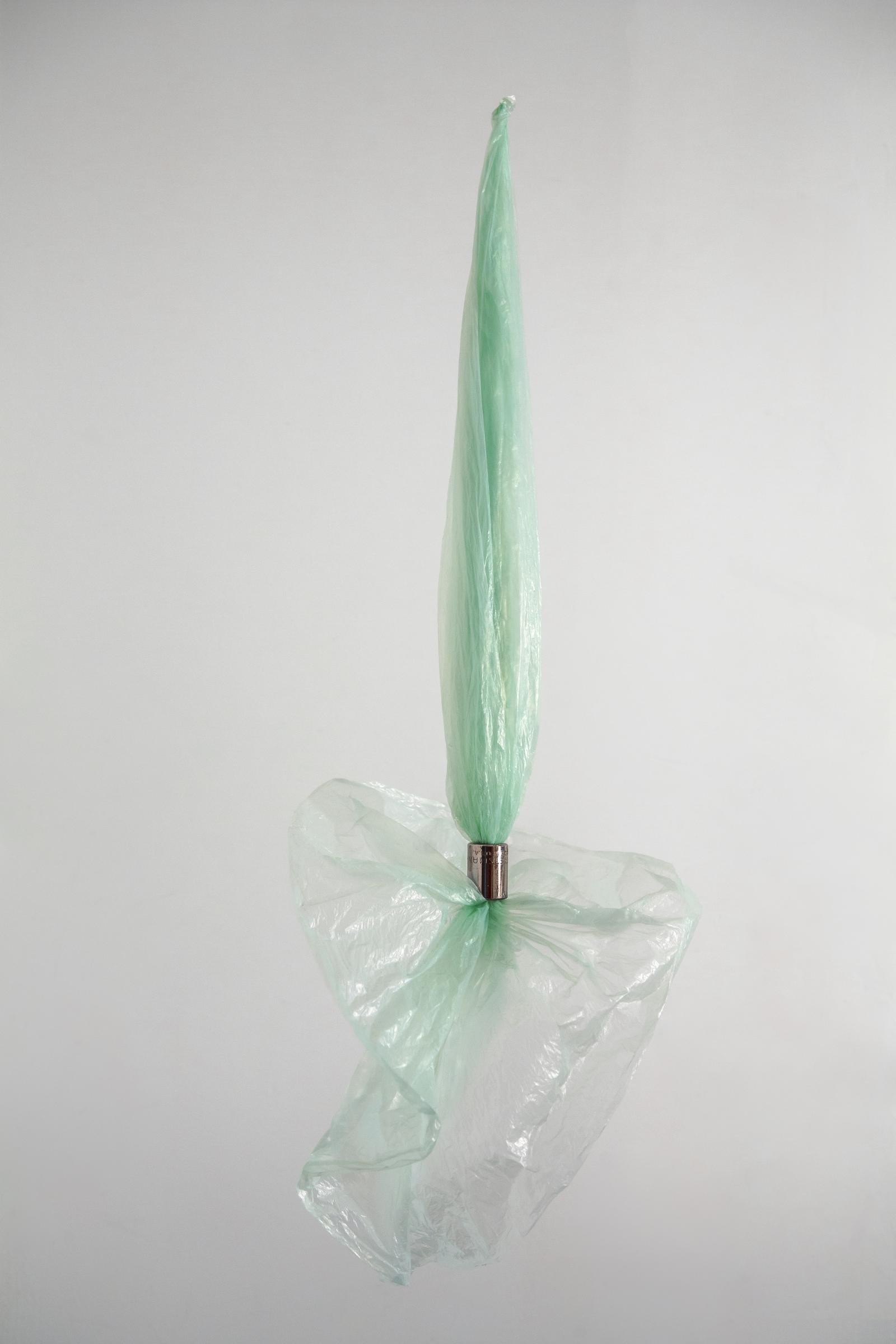 Floating on detritus (2018) is a used light green plastic bag pulled from its closed end through the half-inch opening of a cylindrical power tool socket one inch in height. Hung from transparent fishing line, about two-thirds of the delicate material bunch together under the weight of the metal hardware and gravity to form a top body akin to a folded umbrella. The bottom part of the soft sculpture unfurls like a flower. Its translucent “petals” often catches the slightest whiff of air to set off an inverted pirouette.

This eponymous piece epitomizes the spirit of what I do - to see beauty and potential in the most humble of things.