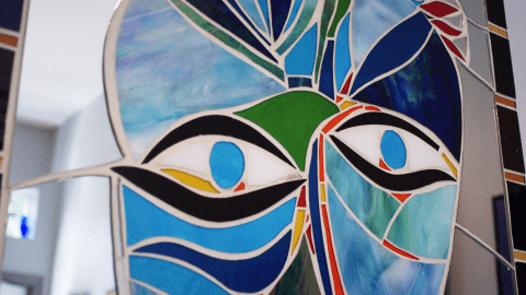 Close up of a blue, black, and green mosaic face 