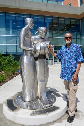Artist Ayokunle Odeleye standing next the metal sculpture
