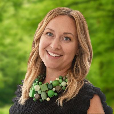 Emily Sollenberger Dobbins headshot. Woman with long brown hair smiling and wearing a black top and green necklaces.