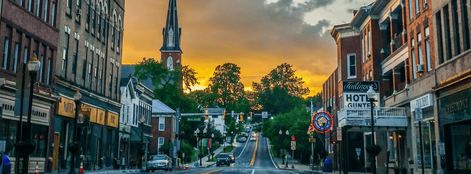 Frostburg First header. Sunset image of an uphill road with building on either side. 