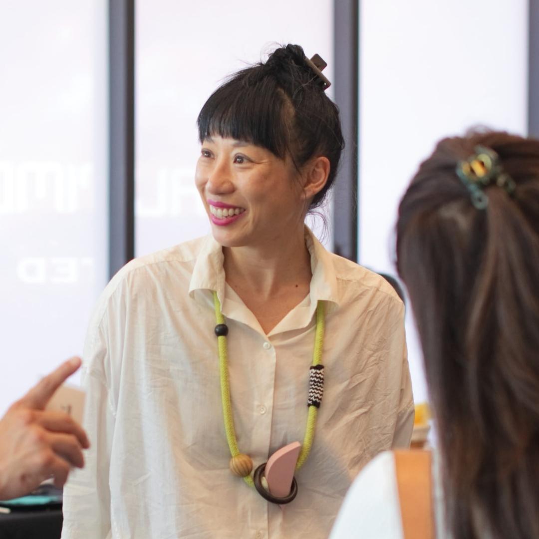 Artist Phaan Howng, asian woman wearing white blouse with top bun and bangs, enjoying time with other attendees at Asia North 2026 (Baltimore City)