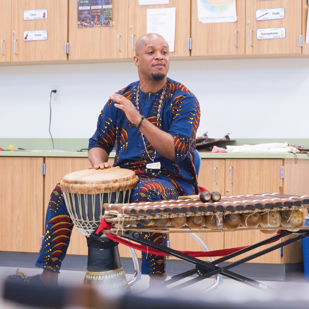 Teaching Artist Roster member, Uasuf Gueye, leading a drum circle with students (Montgomery).