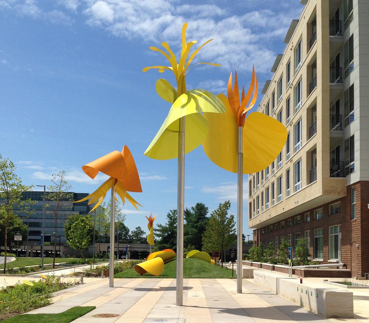 Running along the front of a mixed-use development, the park-like site is intended to be interactive for children and families while serving as landmark for the project. The inspiration for the forms is the tulip poplar. Abstracted petal forms are used at various scale from very small “petals of thought” scattered across the site to freely rotating large petals with seedpods on top of tall poles. Petals are stretched and twisted to form slides and other structures that children can climb over and under.
