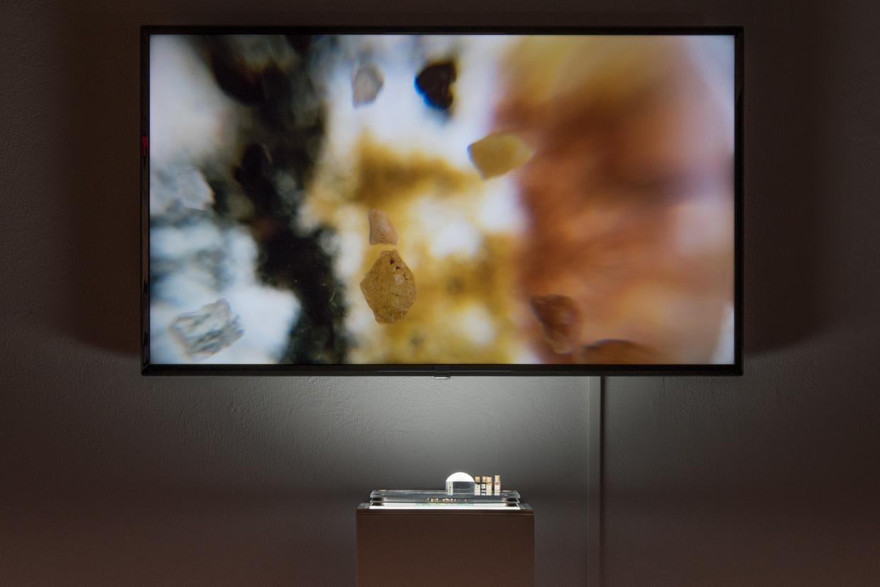Shot at micro level, tiny grains of sand navigate through color-coded "neighborhoods", sourced from the 1937 Residential Security Map of Baltimore. This 20 second video loop is played on a 4K monitor with an accompanying sculpture of the work on a light pedestal with a magnifying globe.