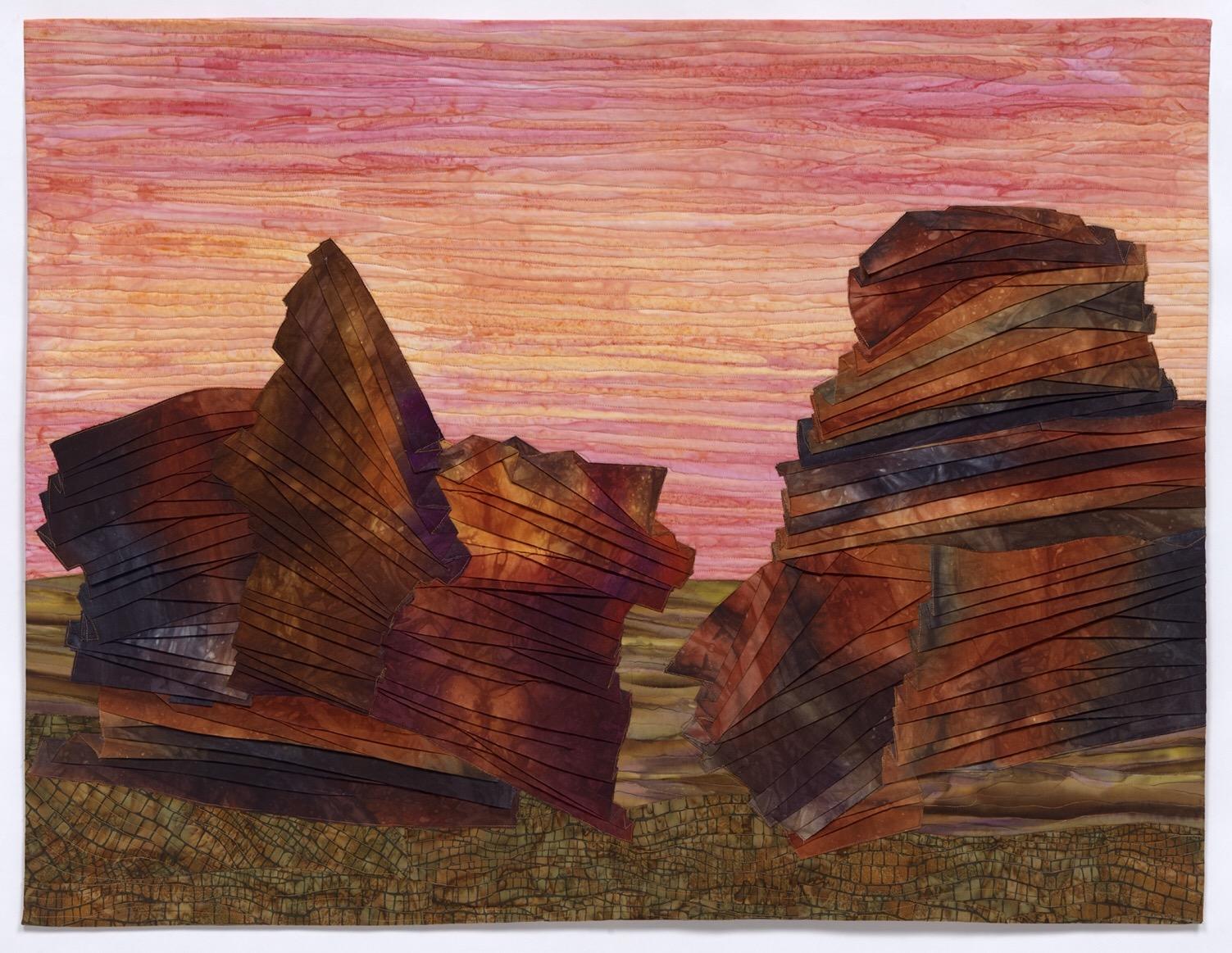 Fiber art collage using hand dyed and batik fabrics, including pleated shapes which look like rocks.
