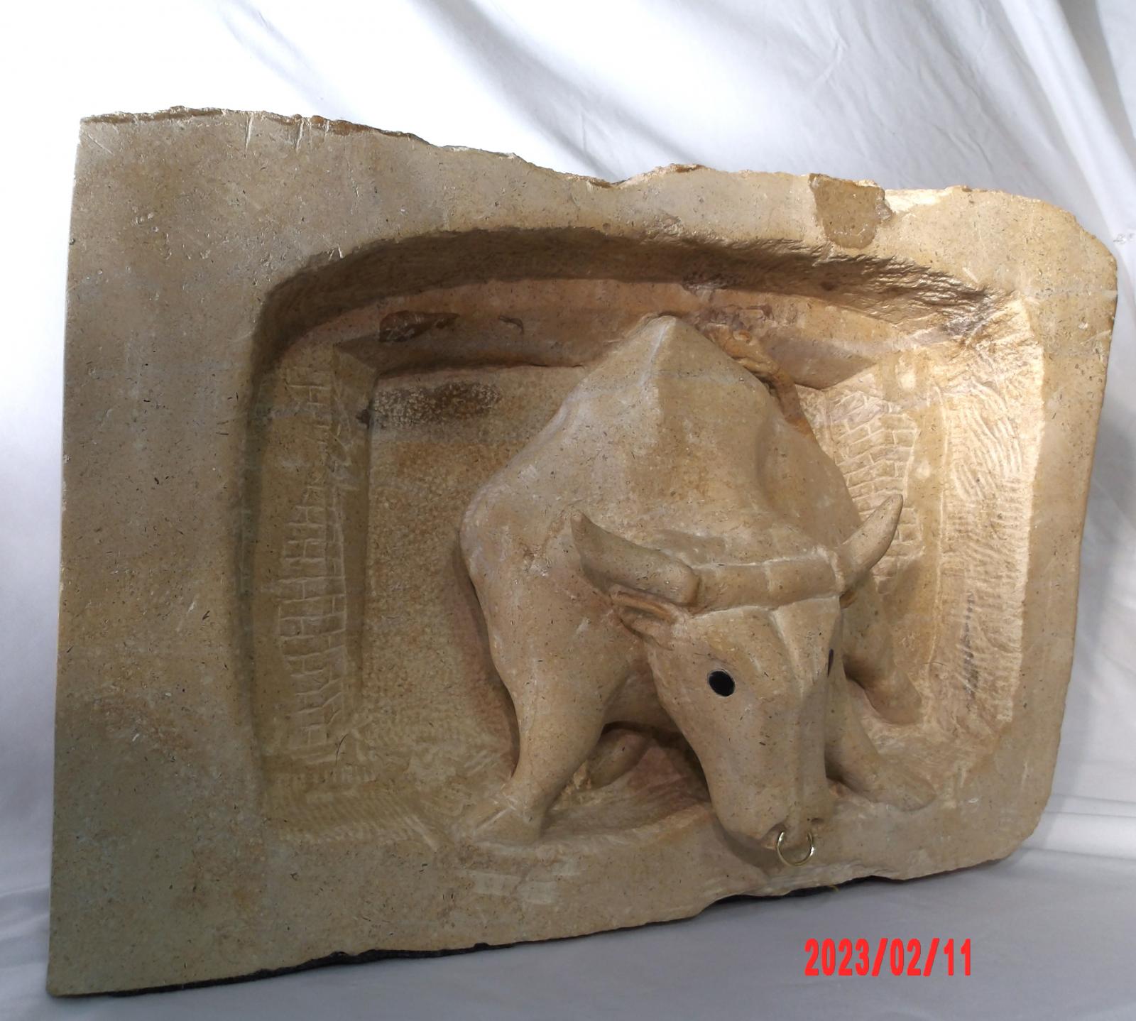 A low relief of a charging bull as it comes through the passageway of an arena.  Scared, confused, and unsure but ready to protect himself.