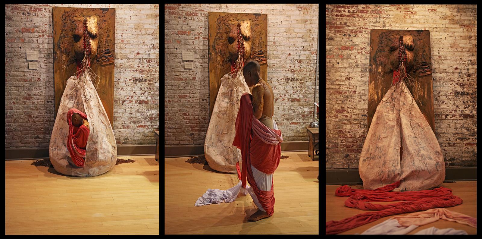 “UNFOLD”
Mixed Media Installation & Performance (Rite of Passage) – Earth, Henna, Hair (Locs from “Grounding Ceremony”), Roots, Fibers, Oil Paint, Acrylic Paint
Approx. 7ft X 3ft X 5ft
June 2006 – June 2016
Unfold documents a metamorphic transition. I worked on Unfold, for a 10 year period.
Unfold began as a cast of my upper body, which I made into a pregnant form. From there, over the years, the piece would evolve based on life experiences, new understandings, and revelations in dreams. During an emotionally tumultuous time in my life, I had a dream that I cut my chest open and took my heart out. In the dream, I seached everywhere for someone who could fix it and put my heart safely back into my chest, but eventually found no one. Upon waking from this dream, I channeled that intensity into this piece, which was still a cast at the time. I mounted the cast to a large wooden panel and cut the chest open.
Over the years the piece evolved. I impregnated the cast with written intentions and words on fabric. I painted it and attached roots and bark. A few months after “Grounding Ceremony” I began to sew up the pregnant torso up with my newly cut locs. As a few more years passed, I opened the body cast again, revisiting and revising those intentions to more positive and life-affirming ones. Then I sewed the torso back up using my locs.
Its final stages of development came as I built a large cocoon attached to a sculptural cast of my “pregnant” torso, sewn together by my hair. I then entered the cocooon, where I spent time in deep stillness. While in the cocoon I wrote words along the inside of its walls with india ink; the drips and painted strokes visibly appearing on the outside surface of this transluscent cocoon. After five hours of being inside of this piece, I (publicly) birthed myself from the cocoon I had created, hand dyed fabric trailing behind me like an umbilical cord.
Not long after birthing myself from the cocoon, I decided to bury the placenta in my yard. The piece is still outside, as the weather & shifting seasons change it daily. Eventually it will fully return to the Earth.
. . . . . . . . . . . . . . . . . . . . . . . . . . .
⠀⠀⠀⠀⠀⠀⠀⠀⠀⠀⠀⠀ ⠀
“The butterfly can help you see that exiting the cocoon suddenly opens a new door. The power of the butterfly lies in transformation and trust. Caterpillars must trust instinctual inclinations without doubt in order to reach the metamorphic stage. The caterpillar is almost completely dissolved by enzyme compounds within the chrysalis, before it can reform into an adult butterfly. Their whole body must be broken down to completely transform!” ~ “The Incredible Journey of the Butterflies”
