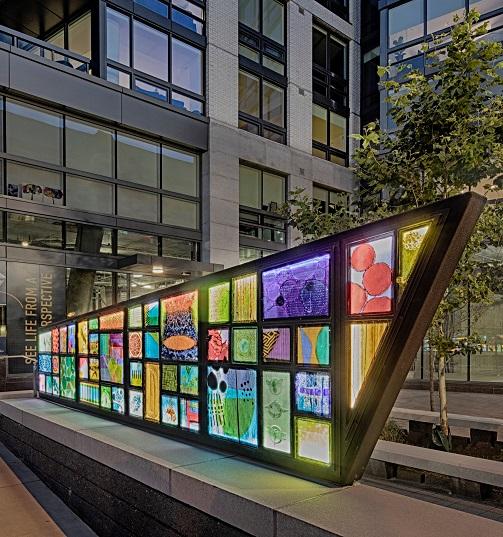 Commissioned artwork sculpture for new Arlington, VA residential/mixed use development. Framing the corner location of the new plaza at Fairfax Drive and North Quincy St. in Arlington, VA, the sculpture is made of almost 100 individual hand cast glass panels set into a bold geometric framework of acute angles that references the sculptural qualities of the new J-Sol building. The sculpture defines the location and creates a new sense of place with the layering of color, light and shadow. Merging architecture and design with their signature material, glass, the overall presentation of the sculpture is aimed to reflect our modern society and urban space.