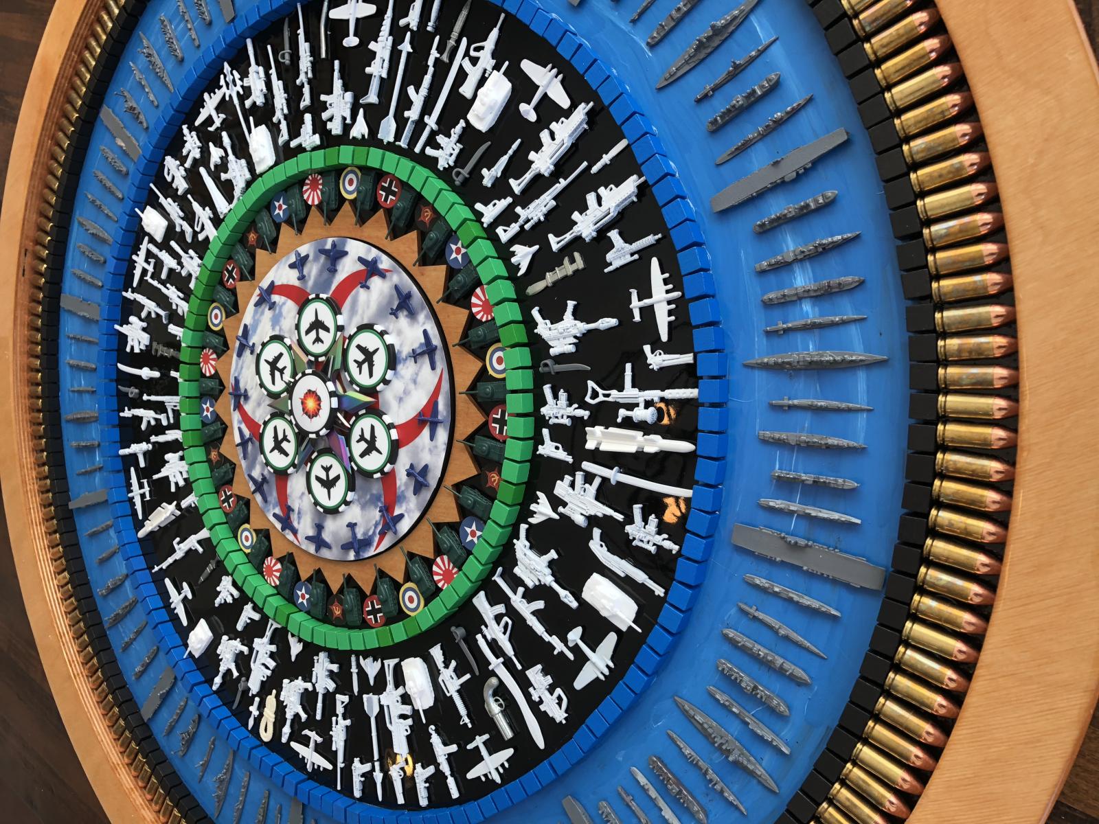 This 32 inch diameter nostalgic collage is titled, “Wargames”, echoing back to the 1980’s movie starring Mathew Broderick. This work is composed from game pieces drawn from all the strategy games we played as children. You can find game parts from Risk, GI Joe, Axis & Allies, Lego, and Clue that ring a center composed of Chinese throwing stars on a field of clouds. The outer ring is made of almost 200 brass jacketed 9mm rounds which have no powder making them a stunning border that is safe to hang on your wall. I hunt for unique pieces from the past and assemble them into complex collages of texture and color creating “Nostalgic Art.” Although many pieces are vintage, others I create by hand at the Baltimore Foundery. Each piece is positioned strategically to create a pattern that draws the work together. Planning takes several months for a new design. Assembly begins in the center and I work outward with construction taking place over several weeks. The completed pattern is then sealed using multi-layer epoxy resin, which creates shimmer and protects the work. The resin also allows you to trace your fingers over the different textures, for both a visual and tactile experience.