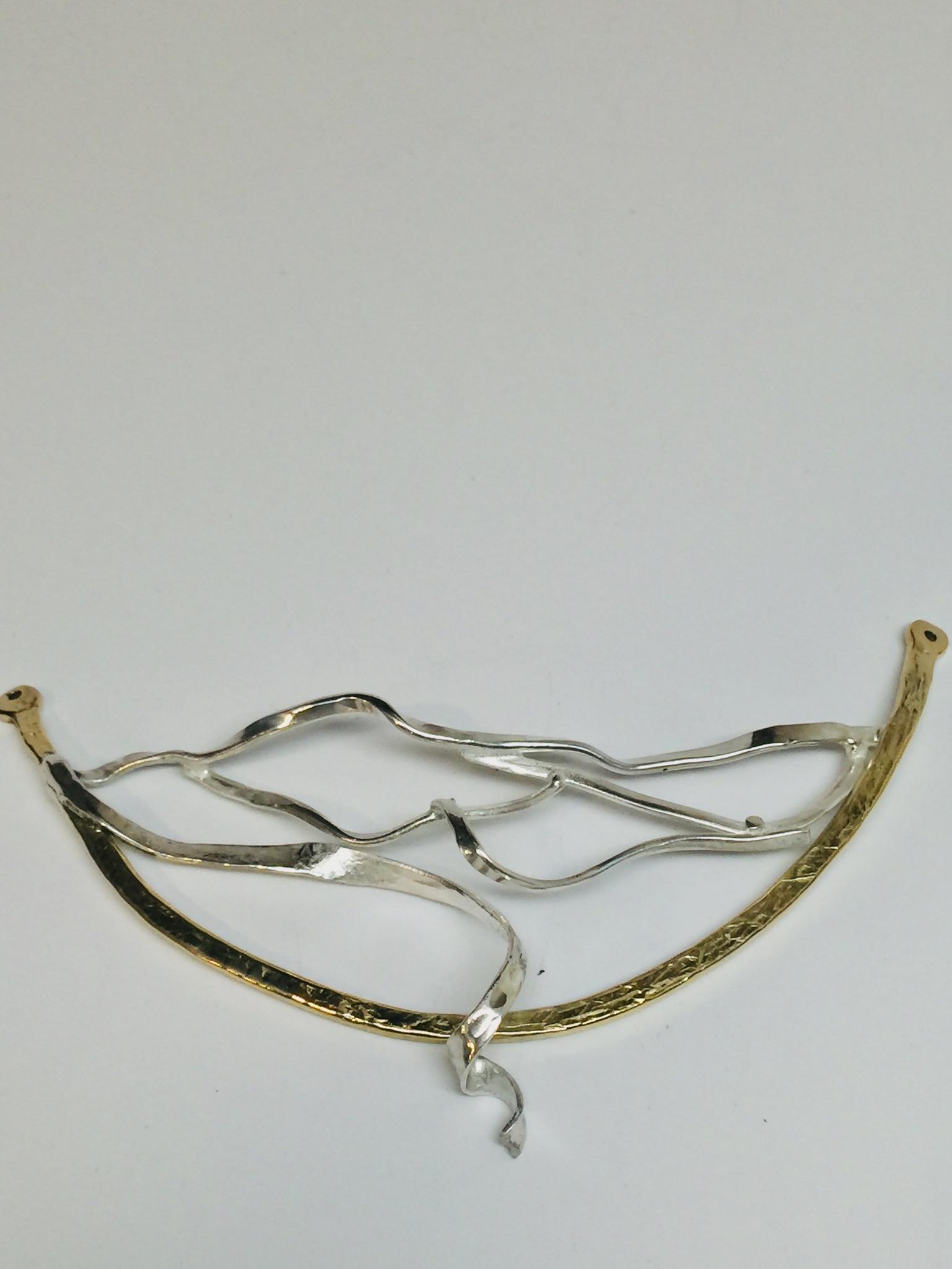 Necklace before attachment of argentium silver chain (hand-made links). The silver in the center of the middle portion of necklace is fused argentium silver scrape that had been heated and forged for other pieces. It was a perfect fit with a little tweaking. It undulates and is a bit 3D. The outline is formed, forged and textured bronze rod. An argentium 12 ga link chain was added.