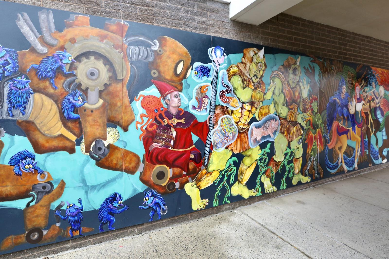 The Mythical March Mural is 140 ft long mural drawn and designed by me with help from over a 100 people from the Long Reach Village Center community in Howard County Maryland. It depicts a huge range of various mythological creatures marching into the doorway of the DoodleHATCH Museum, I prioritized scale and really focused on making the creatures "interact" with each other which really makes the band of characters feel alive. I lead a team of painters and focused on finding each artists strengths and interests then having them work on parts of my composition that I felt would suit them This allowed for a sense of collaboration while still maintaining a unified and coherent vision.