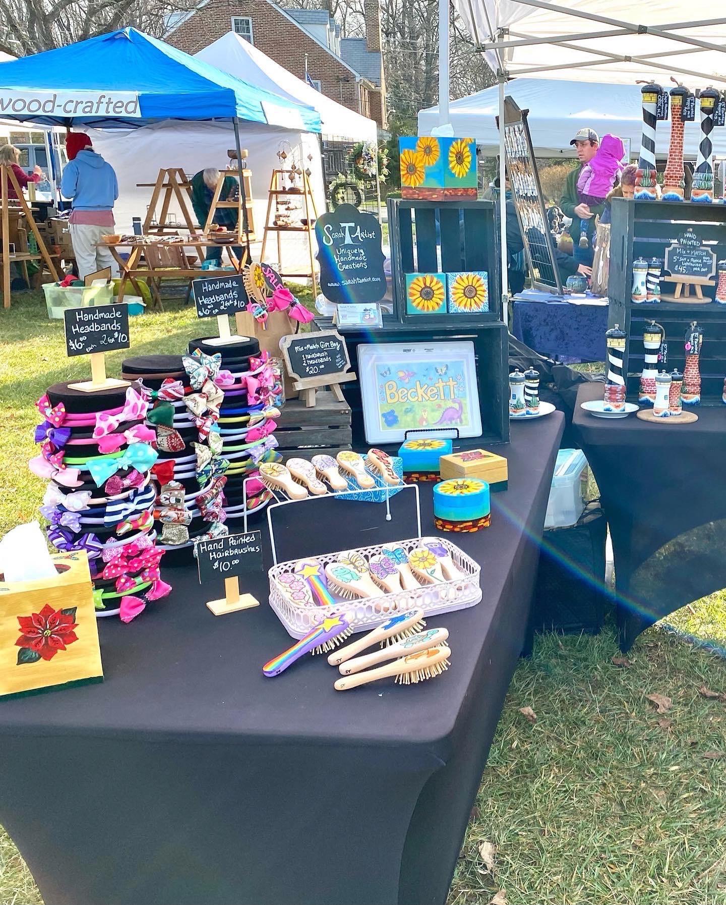 This is a picture of my booth display at the Olney Farmers and Artists Market. It includes many of my painted crafts such as hand painted lighthouse themed pepper grinders, mini canvas paintings, tissue box covers, painted hairbrushes, handmade headbands, and more.