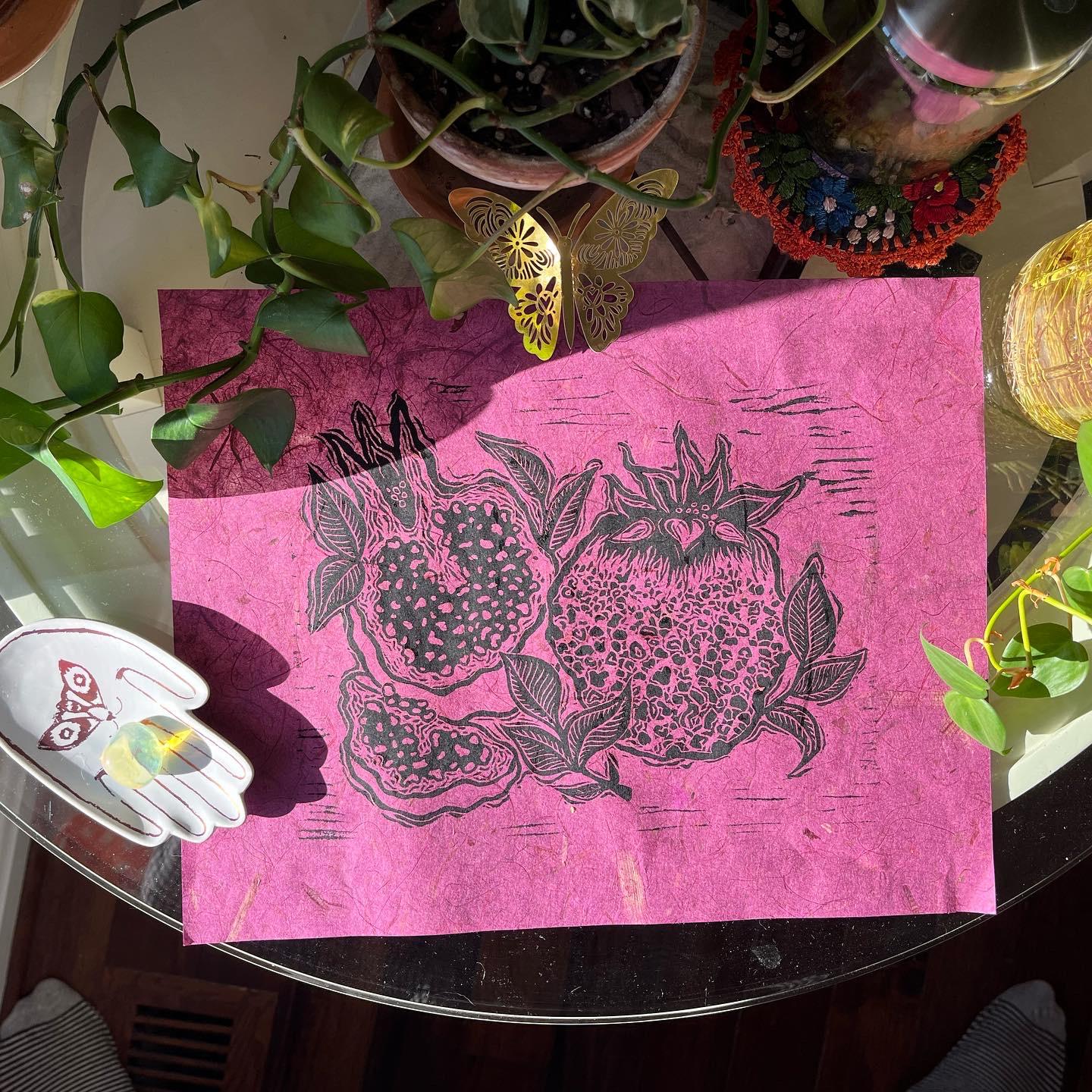 'Abundant Together' is an 11x14 inch hand-carved linoleum block print. The print is hand-pressed onto magenta-colored Lokta Paper.
'Abundant Together' features a linoleum block printed image of artist-inspired textured pomegranates in celebration of the Jewish New Year, Rosh Hashanah. Pomegranates are holy fruits in Judaism and signify many things including the 613 mitzvot, blessings, much prosperity, and the opportunity to do good deeds. 'Abundant Together' was made as an homage to a life of abundance and community safety-- where everyone has what they need and everyone feels safe to be their whole selves.