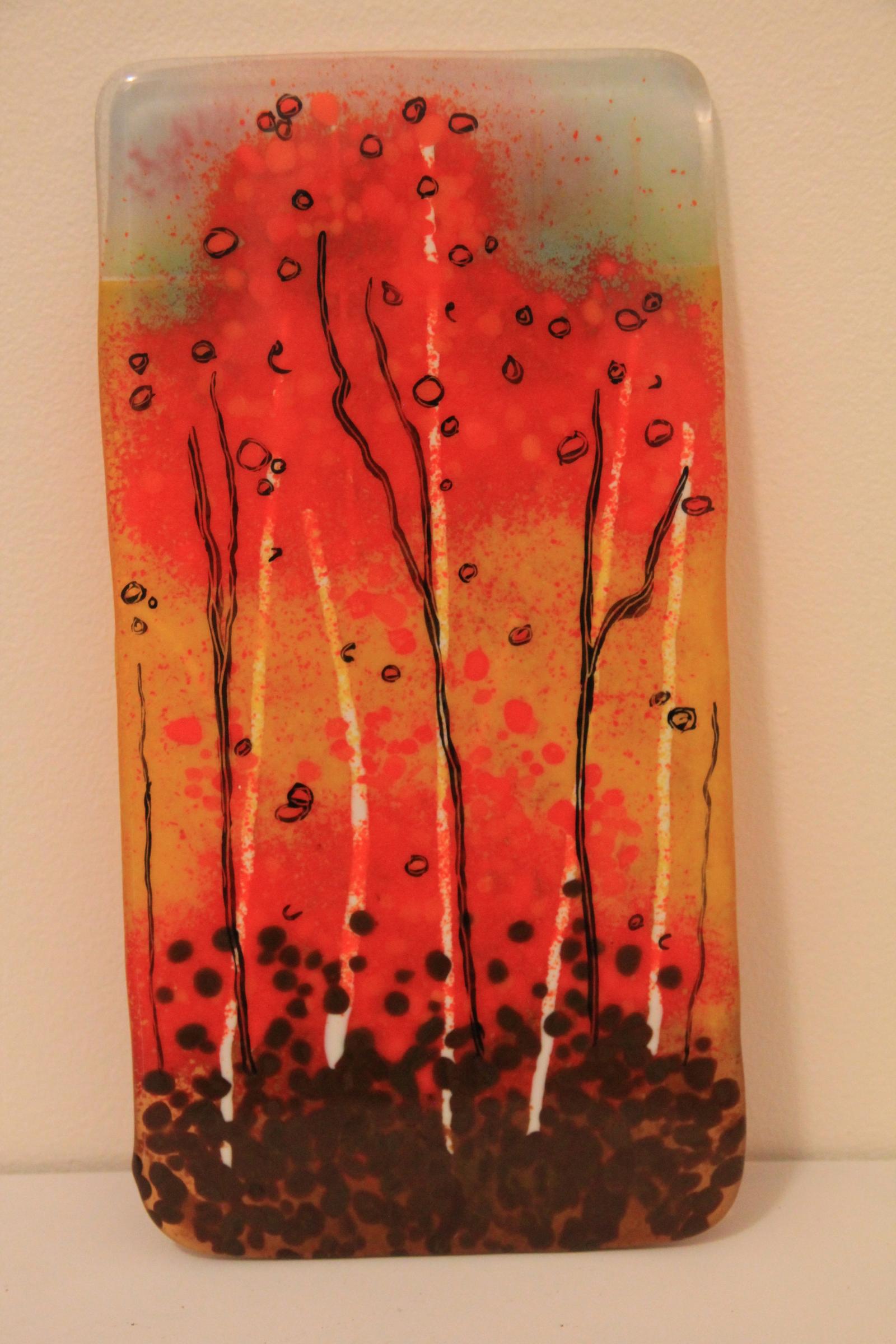 It's quintessential autumn with the fall colors aflame throughout the forest. 

All the color in this piece is from cut and layered glass that has been fired multiple times in a kiln specifically designed for heat work with glass. Black metal oxide was fired into the surface to add texture, detail, and movement. Metal wall mounts have been attached to the back for easy and transparent hanging. 12" x 5"