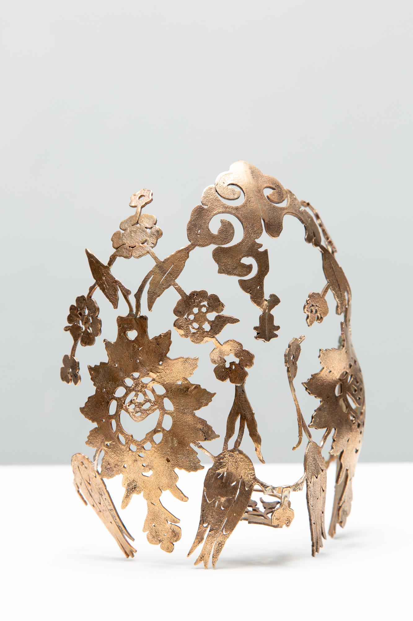 Artist Sera Boeno culminates six years of artistic exploration about gender-related power struggles in “Kelimeler Kıyafetsiz (:Words Naked/Are Not Enough)”. Using her native Turkey as inspiration, the focal point of Boeno’s exhibition is a sculptural installation adapted from the altar of Pergamon, a masterpiece of Hellenistic architecture excavated from Bergama in the Ottoman Empire (Izmir in current day Turkey) and currently held by the Pergamon Museum in Berlin, Germany. Emblazoned with quotes from Turkish media about women, Boeno’s monument serves as a stage for female performers wearing bronze ornaments of domination and torture that are embellished with delicate patterning found in Turkish illuminated manuscripts and textiles. By casting her performers as literal “pillars” of a monument dedicated to female subjugation, Boeno considers the myriad ways in which power dynamics are made manifest, whether through the essentialization of the East by the global West, or through the silencing and omission of women from representation; a story that is neither new, nor one that is exclusive to Turkey.
