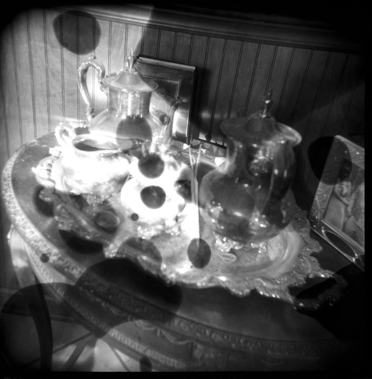 chemically altered silver gelatin print of a sterling silver tea set