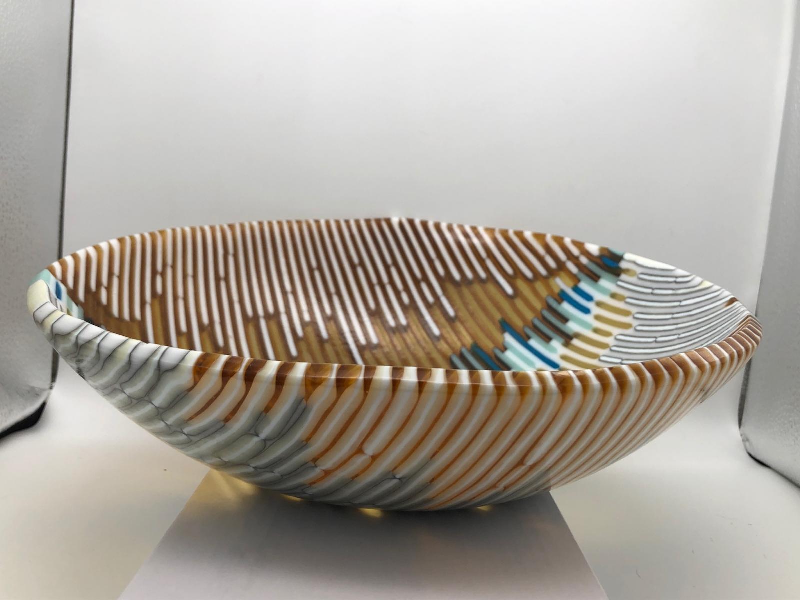 A bowl created by using different types of reactive glass that was fused and slumped to its final look. The bowl is food safe.