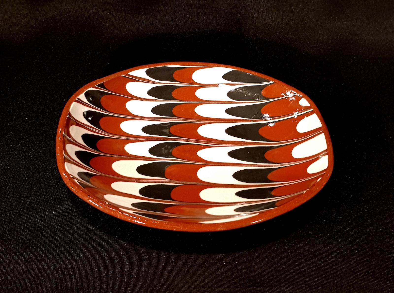 This piece is a very rare example of a slipdish, or dish finished with slip. What makes it rare is its pattern in red, white and black slip, which is very hard to do. It's one of two kinds of feathering found on slipware, the other being "combing" as the English call it.
Fired to cone 02 in oxidation with a clear glaze.