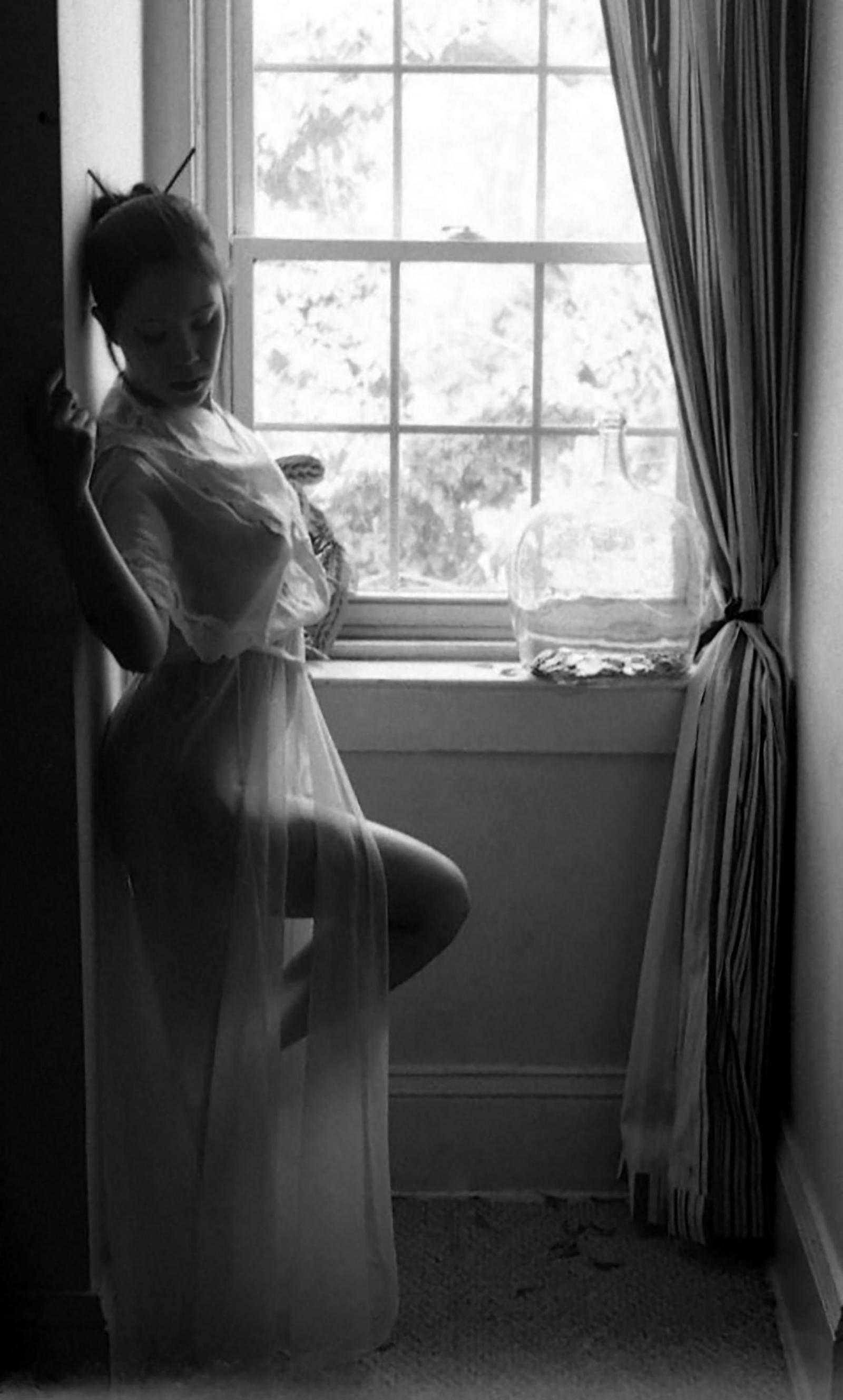 Lady leaning on a wall next to a window