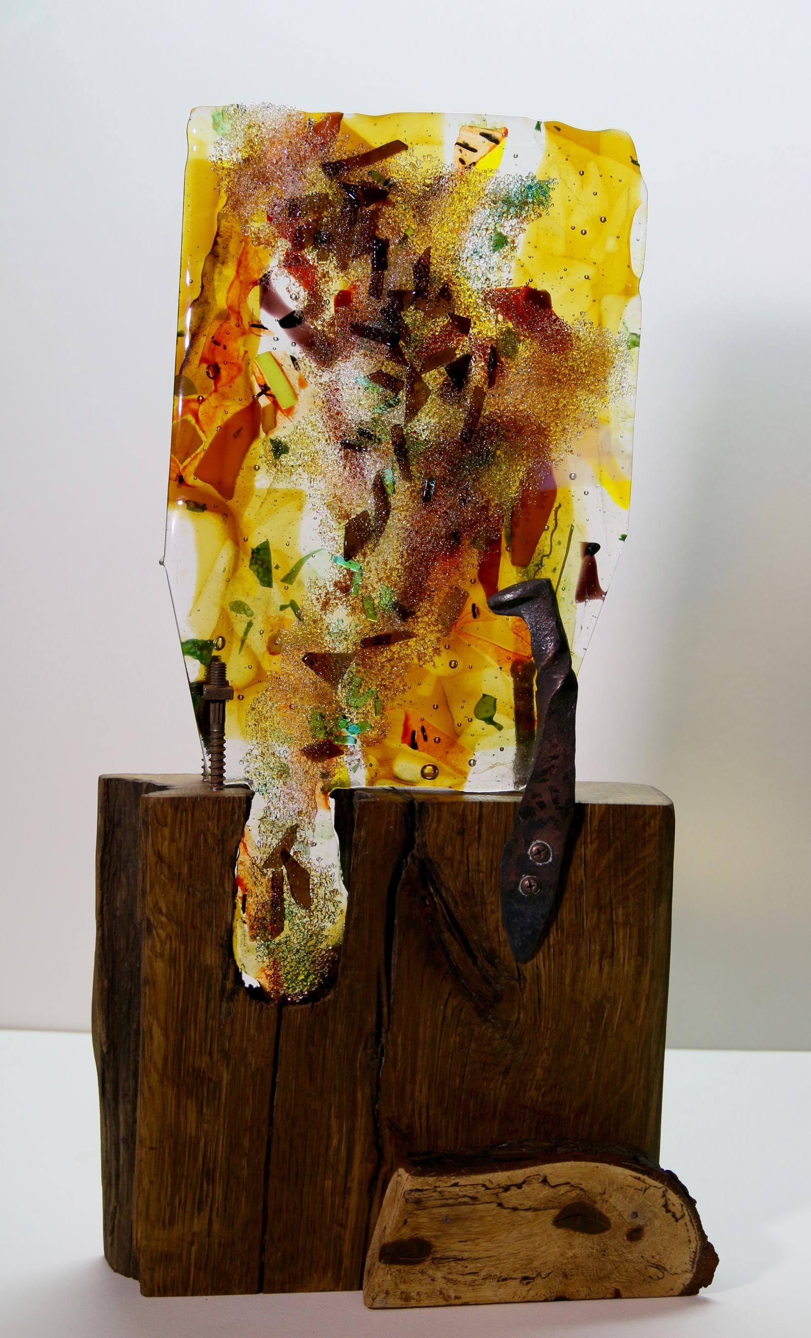 Fused Glass sculpture of amber and earth toned glass on a large chunk of hard wood oak. Held in place by forged railroad spike and large rusted bolts