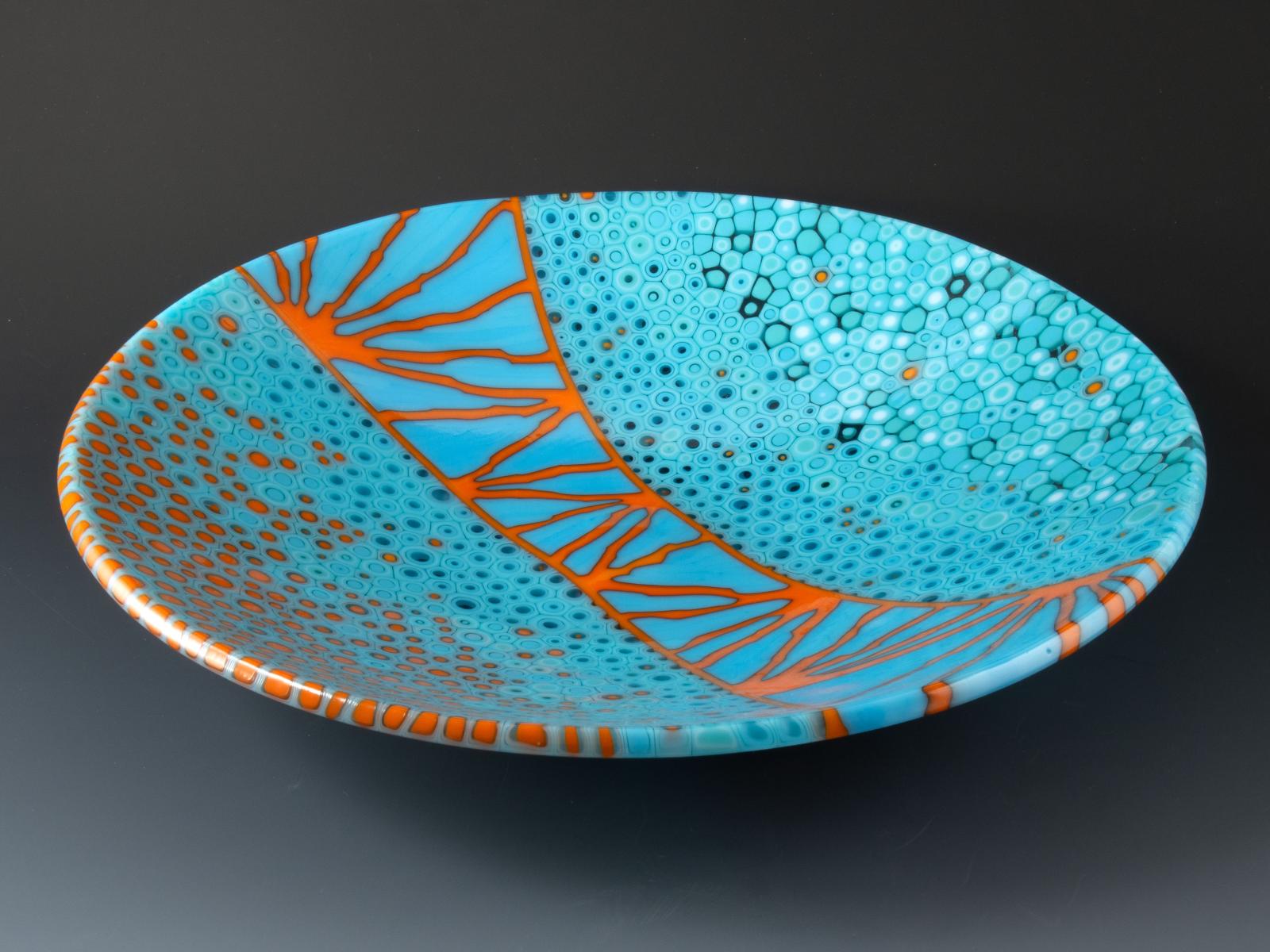 A field of glass murrine transitions from turquoise to tangerine as it sweeps across the bowl, divided by a meandering ladder of blue and orange, reminiscent of the Golden Gate Bridge.

The glass cylinders in this bowl are sections individually cut from hand-pulled glass cane, which I create by heating glass to 1500 degrees and pulling it into rods while molten in a modern-day adaptation of the 16th century techniques of the Murano glassmakers. The gradient of murrine as it moves around the bowl reveals a chronology of the glass cane as it emerged from the crucible.

Fused, cold worked and slumped.