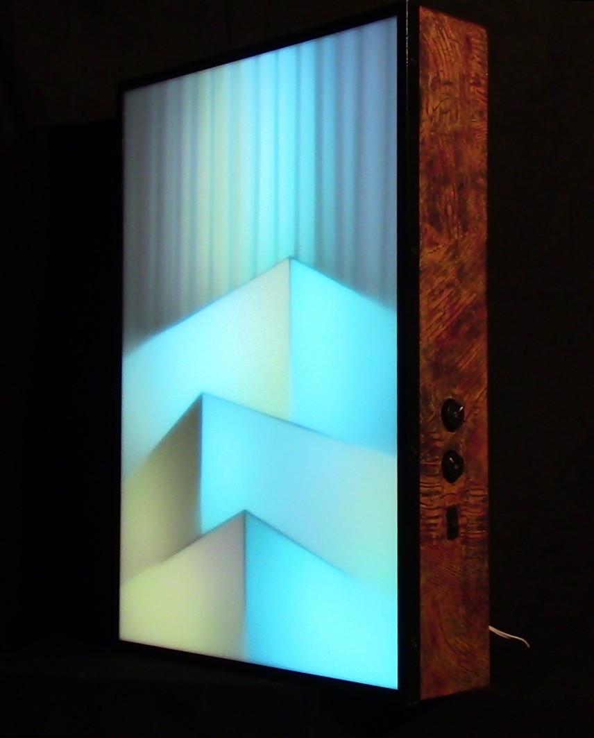 "Urban Breeze" is a light-painting made with RGB LED strips behind a diffusing acrylic screen.
The image shows  the cabinet with the luminous screen on front. User controls on the side are a knob for brightness, a knob for speed of color-change, and on-off switch.  Colors of the image change slowly and continuously.

