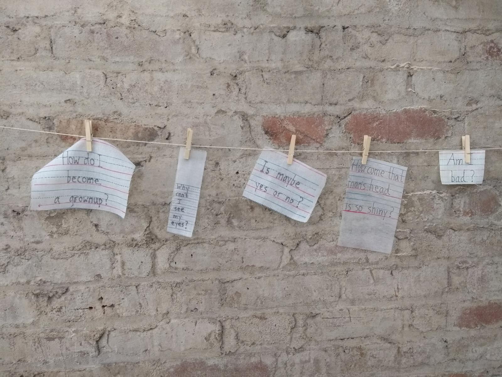 children's questions screen printed onto various fabrics and hung from a clothes line