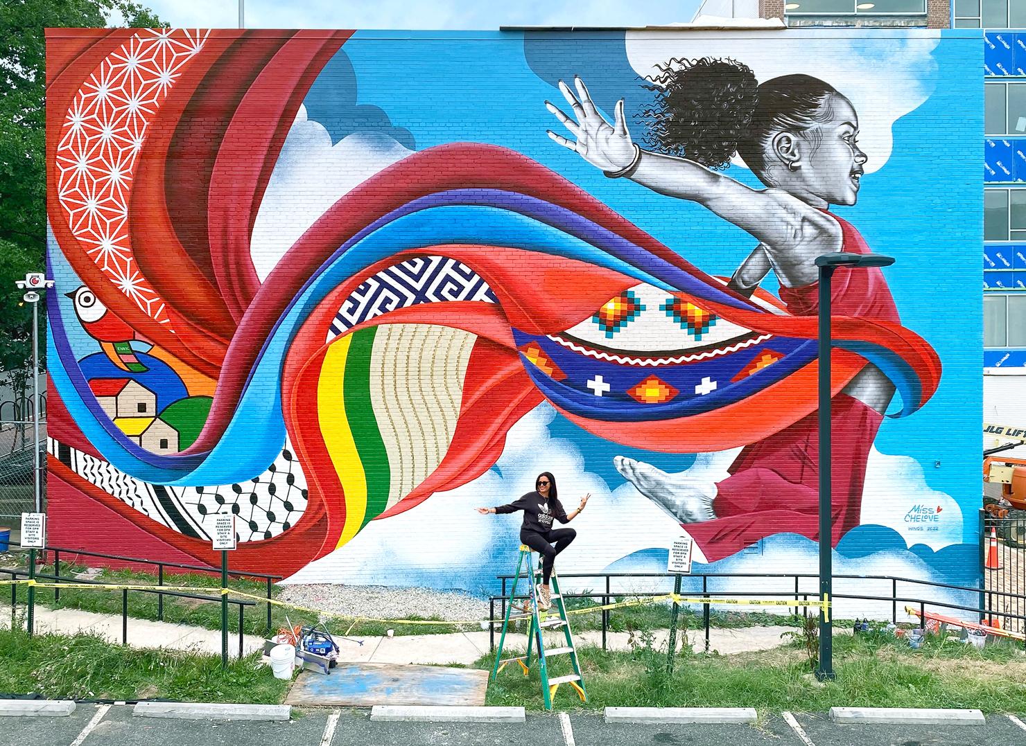 “Wings” is a 52’ x 25’ exterior mural located in the Capitol Hill/H Street district at School Within School at Goding Elementary, located at 920 F St NE, Washington, DC 20002. This mural was painted in summer 2022 for the DC Department of General Services’ Percent-For-Art Program. 