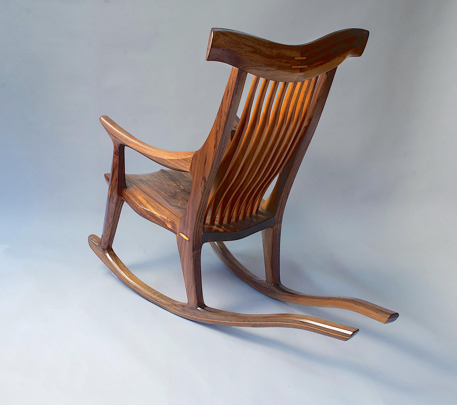 Hand sculpted rocking chair in black walnut with contoured cherry spindle back and shaped laminated rockers.