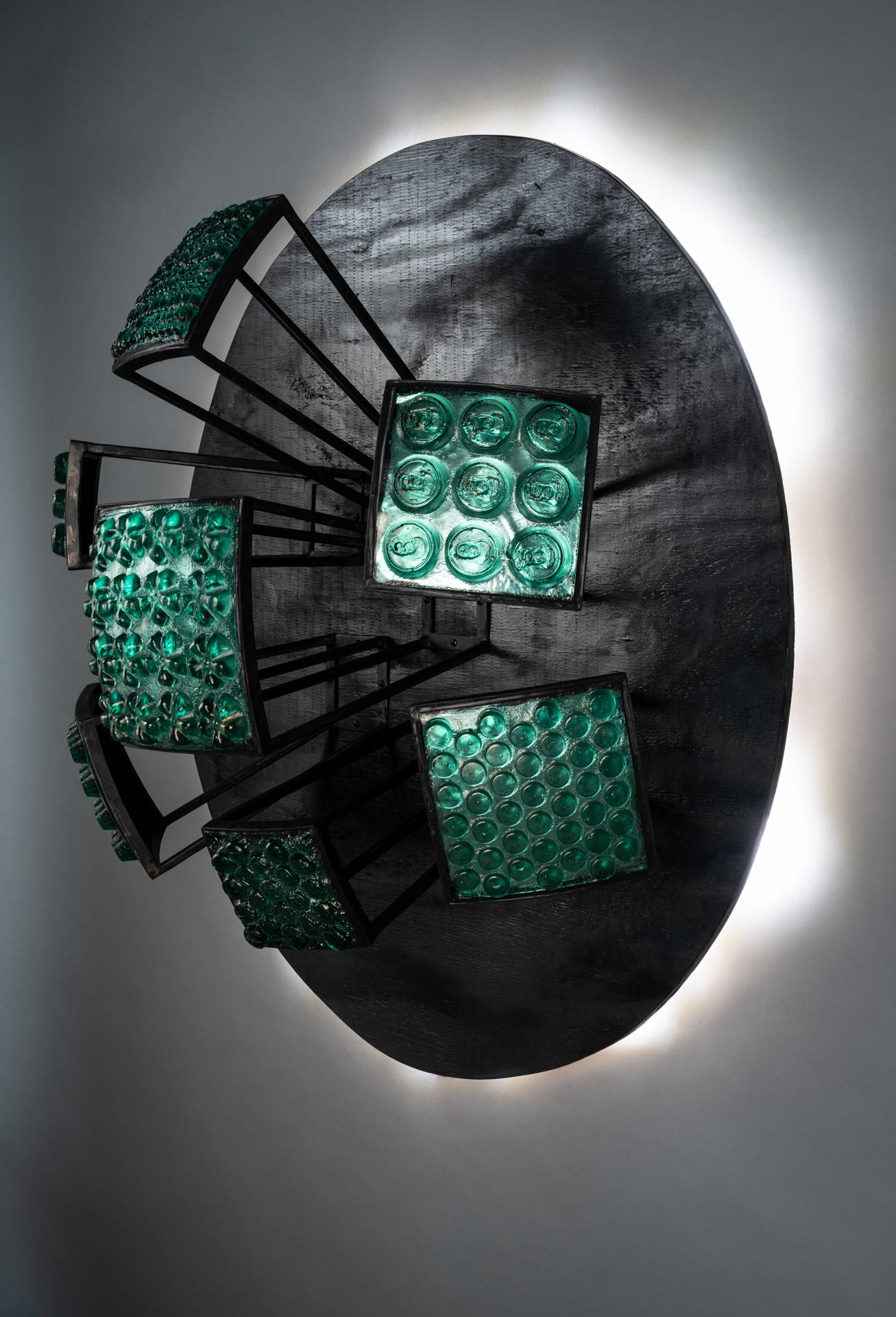 This piece references the vast amounts of material used for packing of goods, that ends up discarded instead of reused or recycled. The backlit circle reminds us this happens all over the world