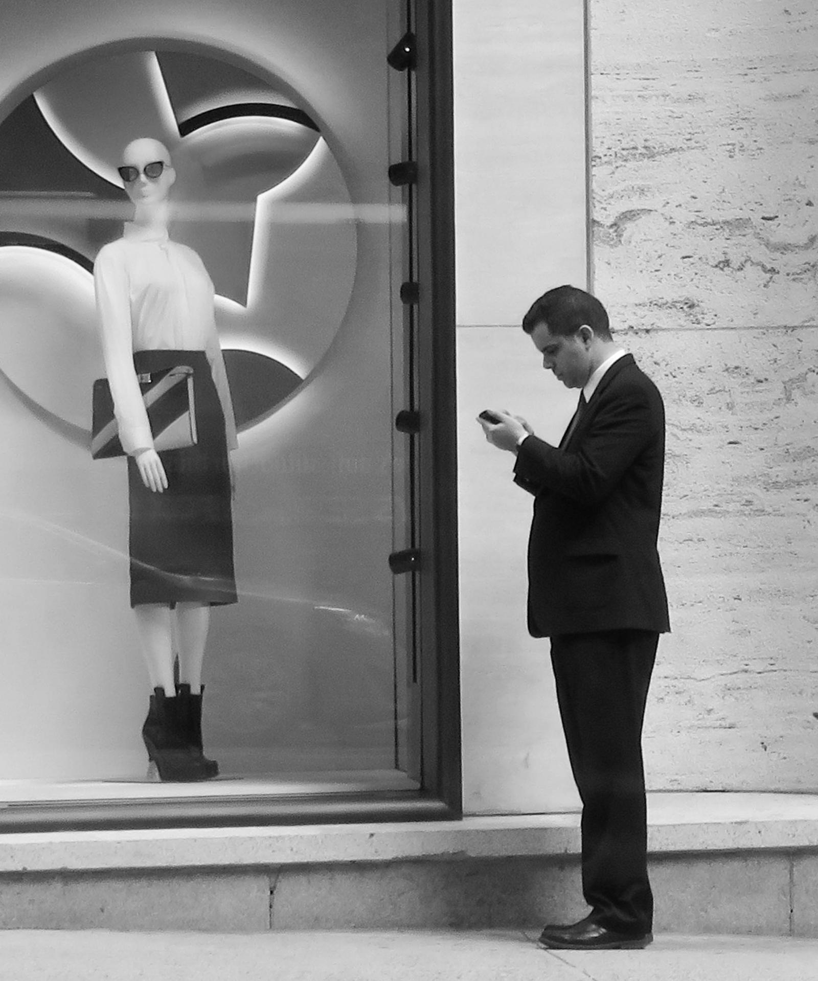 Transfixed by his cellphone, this pedestrian became as immobile as the mannequin in the store window.  It seemed he was trying to communicate with it on it's level.