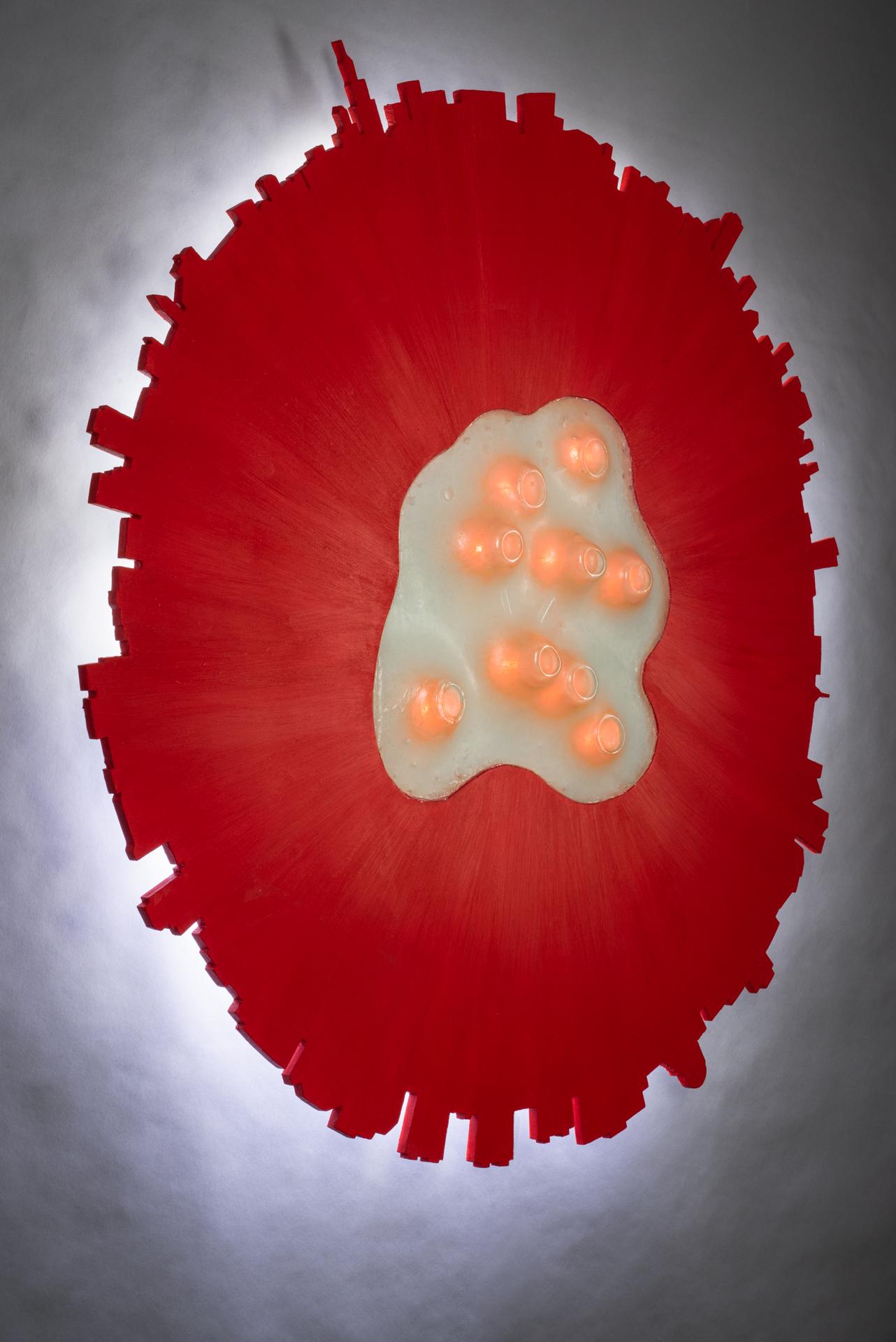 This wall mounted piece consists of a recycled cast glass center with flickering lights. This is surrounded by recycled carved plywood with acrylic paint and backlighting. The stark cityscape backdrop contrasts with the warm organic center, suggesting 2 different ways of living. Some have compared the flickering orange lights to the COVID-19 virus with a New York skyline backdrop.