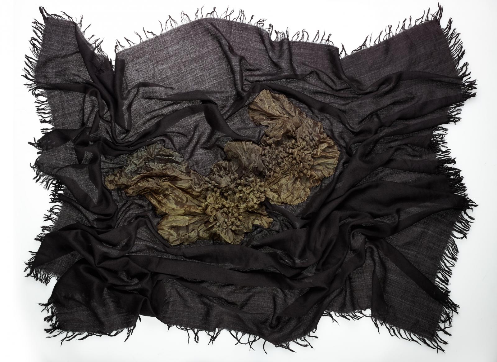 Like the forest floor after a long and refreshing rain, this scarf is dark and shiny, exuding the spirit of new life and the beginning of growth from its depths. It is inspired by the epidermis of the forest, with its dual textures, the leaves of Shibori hand-pleated polyester and the essence of soil influenced cashmere wool. The wearable art piece gives a sense of depth and  bestows true comfort.  This design is an excellent option for any moment where fashion is quintessential yet a soft and elegant quality is also the aim.
