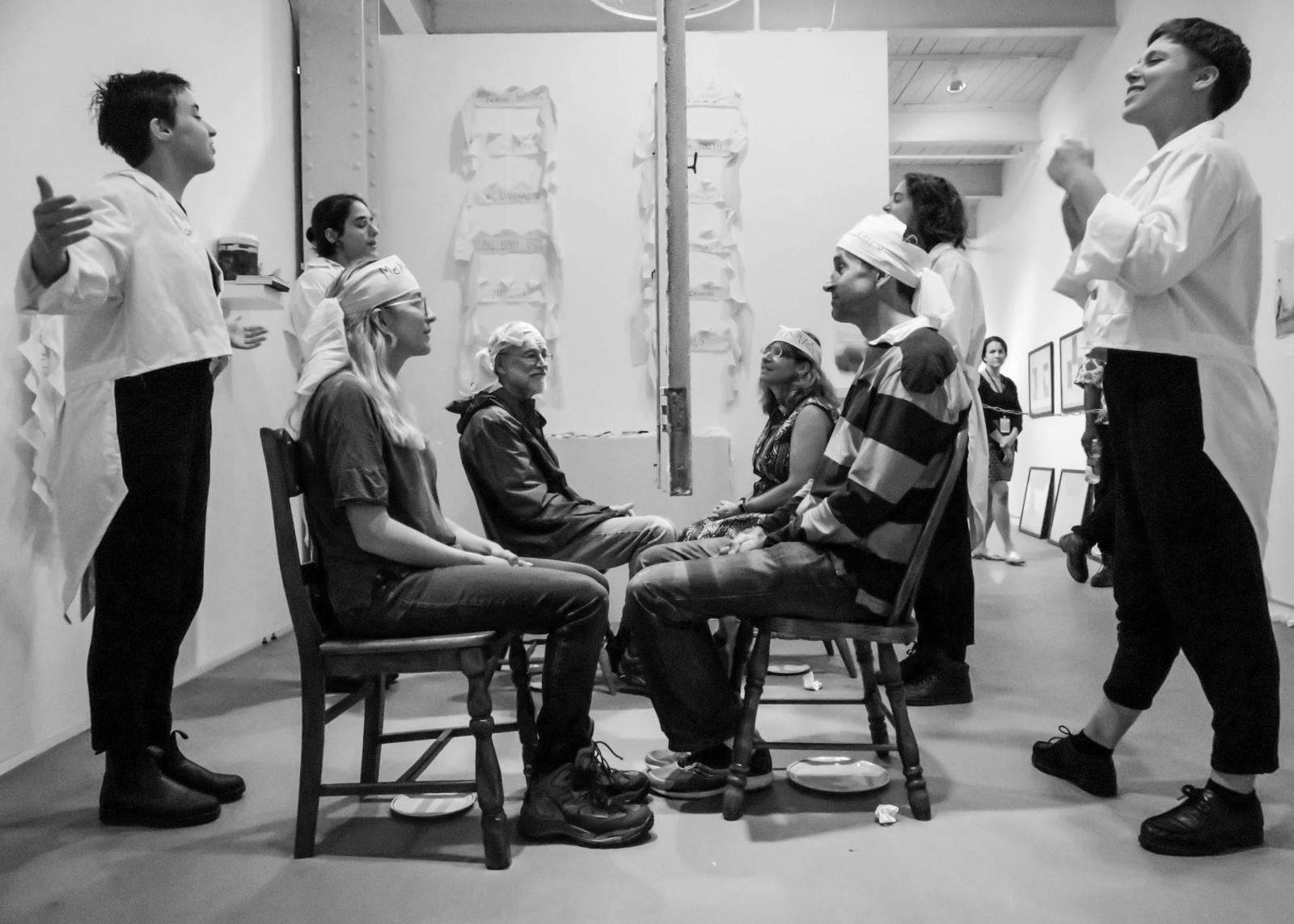Over the course of 3 hours, the applicants welcomed groups of 4 randomly selected participants to join in the rituals of Too Day, the only holiday celebrated solely amongst strangers. In the image, the applicants introduce their participants to their New Best Stranger, a fellow participant who will interact with them through a pane of glass. This performance premiered at the 23rd Annual Cucalorus Festival in Wilmington, NC, and was performed at the 2018 Janet and Walter Sondheim Semifinalist Exhibition at the Maryland Institute College of Art.