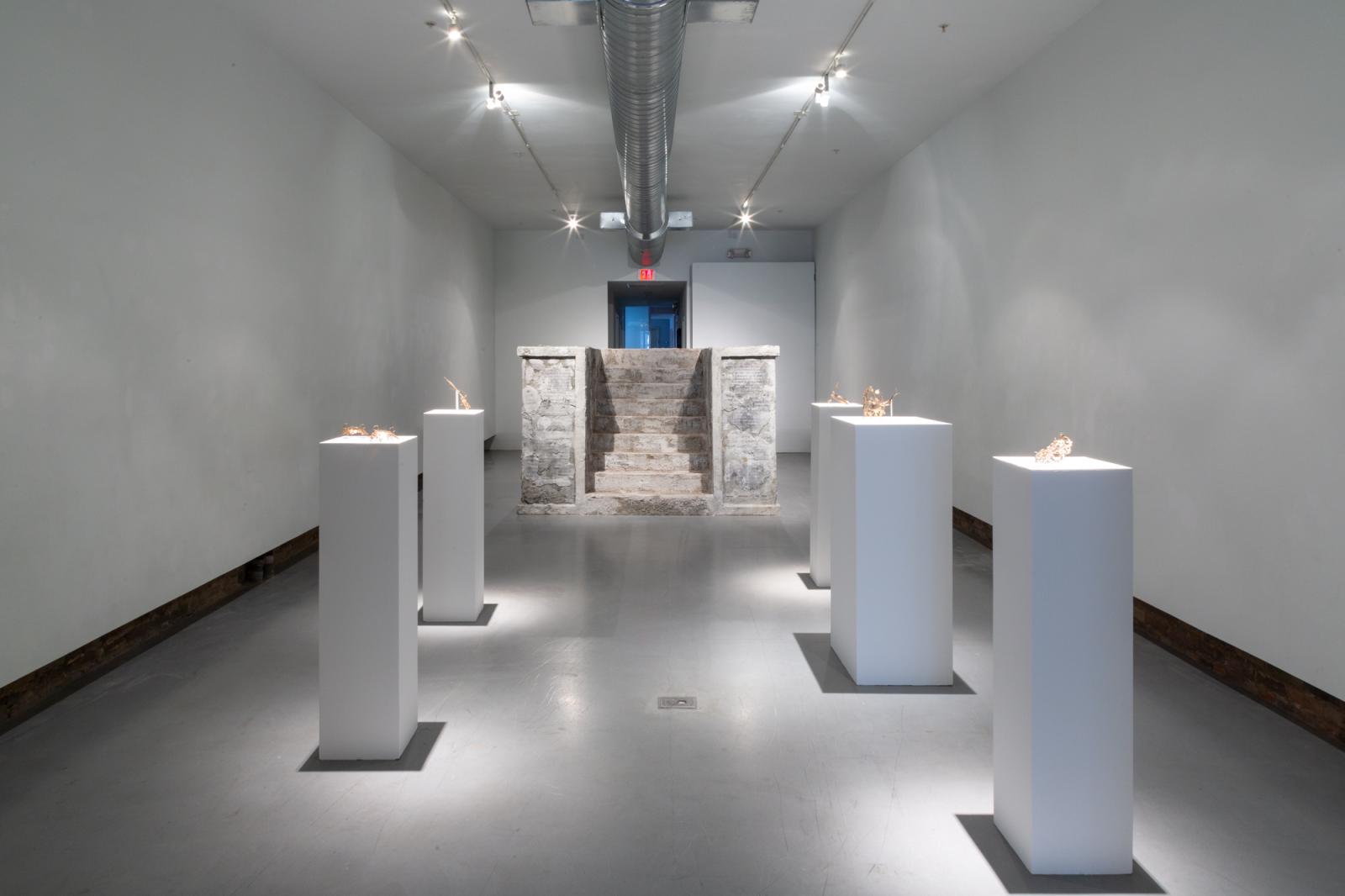 Artist Sera Boeno culminates six years of artistic exploration about gender-related power struggles in “Kelimeler Kıyafetsiz (:Words Naked/Are Not Enough)”. Using her native Turkey as inspiration, the focal point of Boeno’s exhibition is a sculptural installation adapted from the altar of Pergamon, a masterpiece of Hellenistic architecture excavated from Bergama in the Ottoman Empire (Izmir in current day Turkey) and currently held by the Pergamon Museum in Berlin, Germany. Emblazoned with quotes from Turkish media about women, Boeno’s monument serves as a stage for female performers wearing bronze ornaments of domination and torture that are embellished with delicate patterning found in Turkish illuminated manuscripts and textiles. By casting her performers as literal “pillars” of a monument dedicated to female subjugation, Boeno considers the myriad ways in which power dynamics are made manifest, whether through the essentialization of the East by the global West, or through the silencing and omission of women from representation; a story that is neither new, nor one that is exclusive to Turkey.