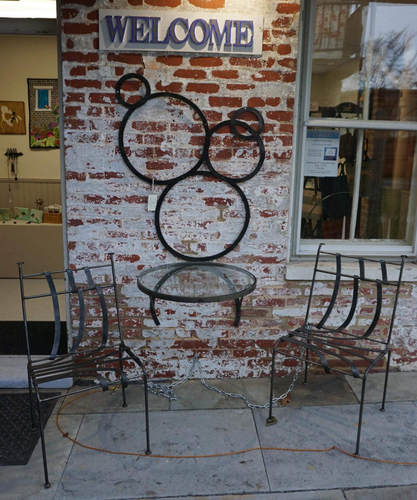 A wall-mounted table with glass top and two chairs