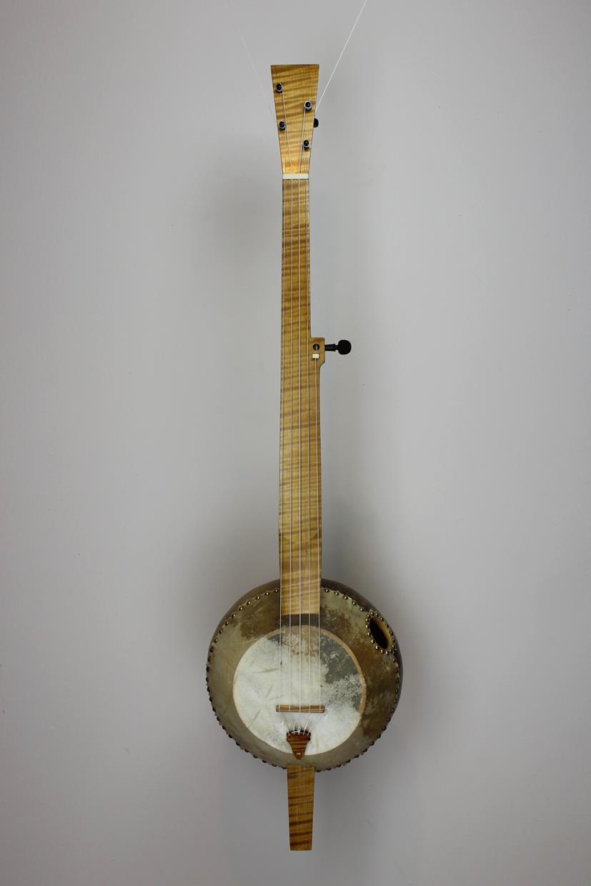 Neck cut from raw maple, stained, finished and fit to gourd. Gourd cut open, cleaned out and prepared for goat-skin soundboard. Goatskin soaked and stretched over opening in gourd. Strings stretched from handmade tailpiece, over handmade bridge and nut then to tuning pegs.