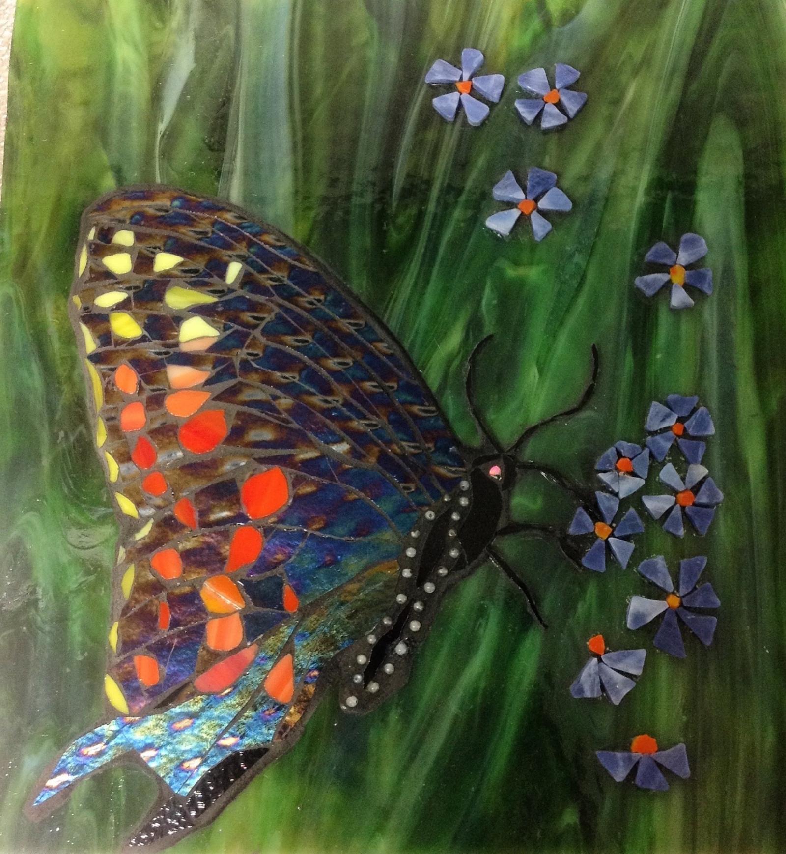 Stained glass mosaic butterfly using Iridiscent black glass, beads, and frit on stained glass background