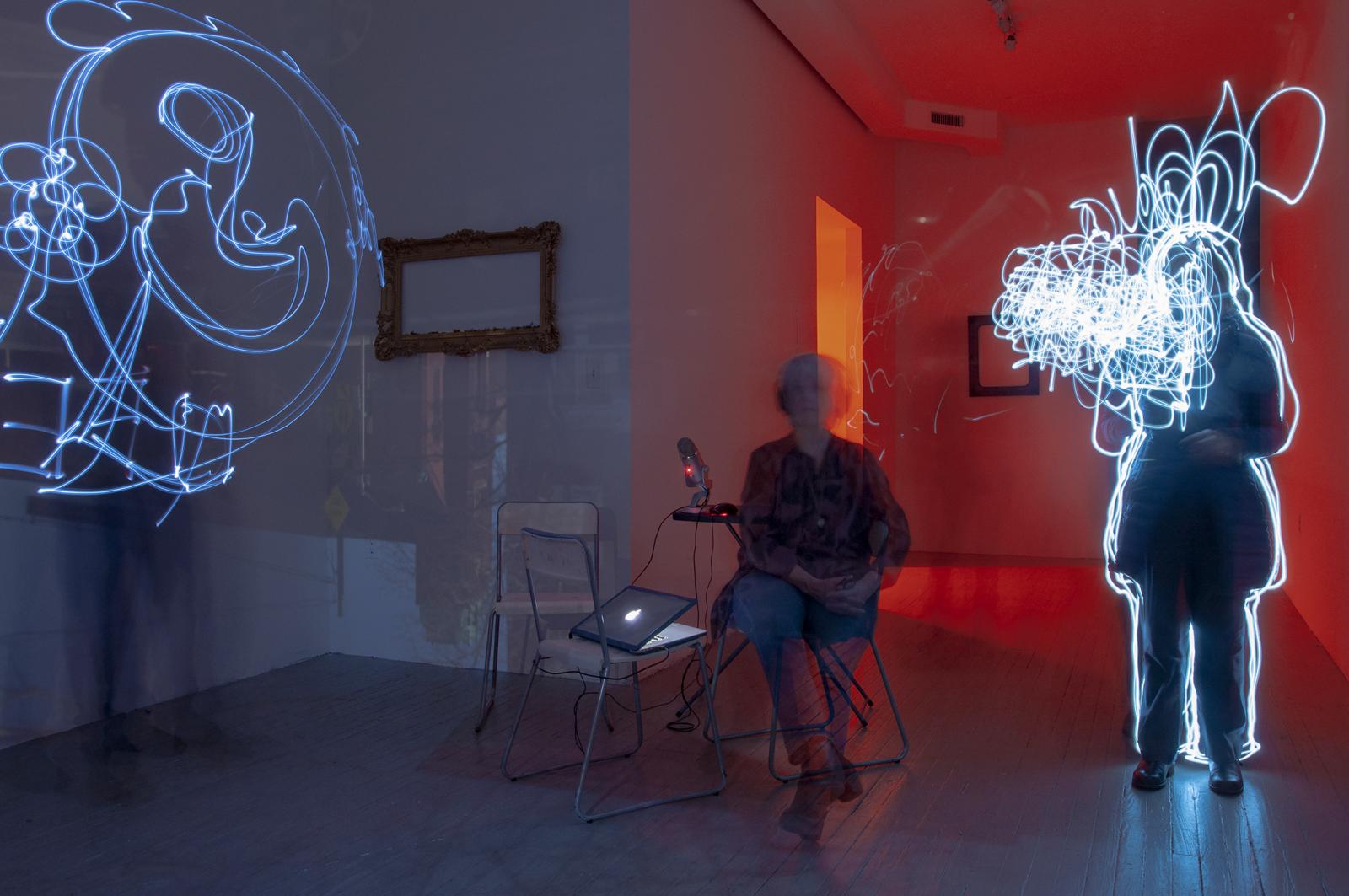 This photograph is an 8 minute exposure of people "writing" in the air with clip lights. They were prompted to express their thoughts on how ageing affects their identity and interaction with other people. The room was a temporary Camera obscura, an installation that blocks all ambient light and projects the scene outside into the space, over the walls and everyone who is there.