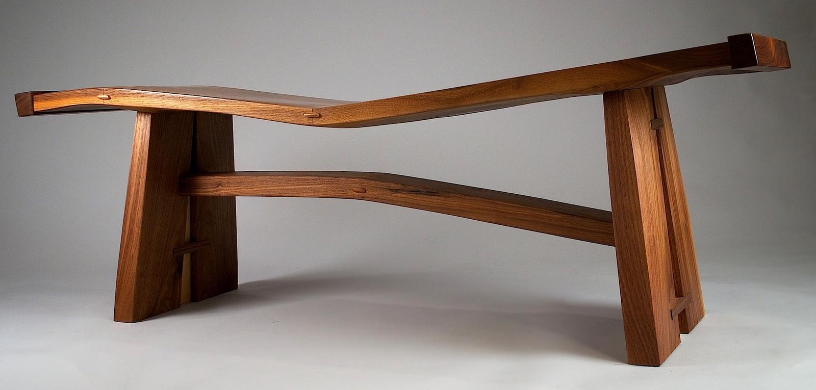 Wave Bench is a study in curves and angles. The seat is thick black walnut, angle cut in the center, rejoined with a series of tenons and splines creating its distinctive wave. The rail under the seat is curved at a reverse angle to the seat.  The base is walnut slab, split and tied by cherry bands.