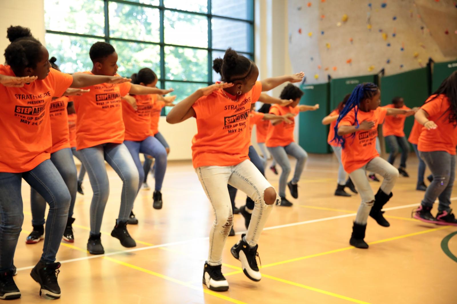 A group of students dancing in sync in a gymnasium. 